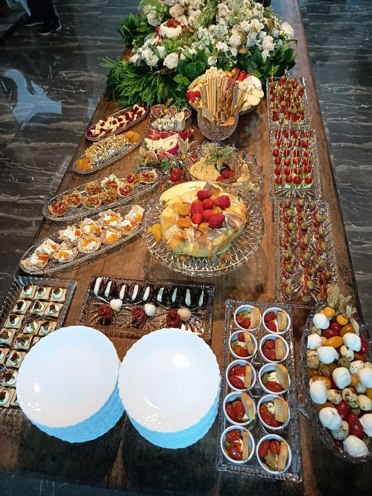 Mesa completa com pequenas porções e arranjos florais
